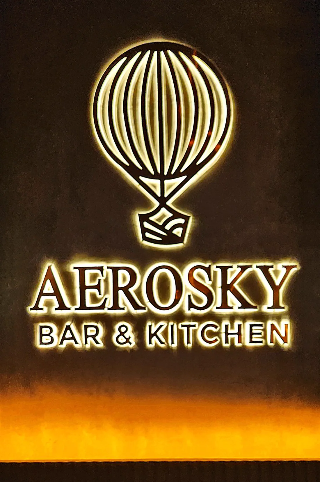 The Aerosky balloon mark and wordmark, backlit on a ribbed wall