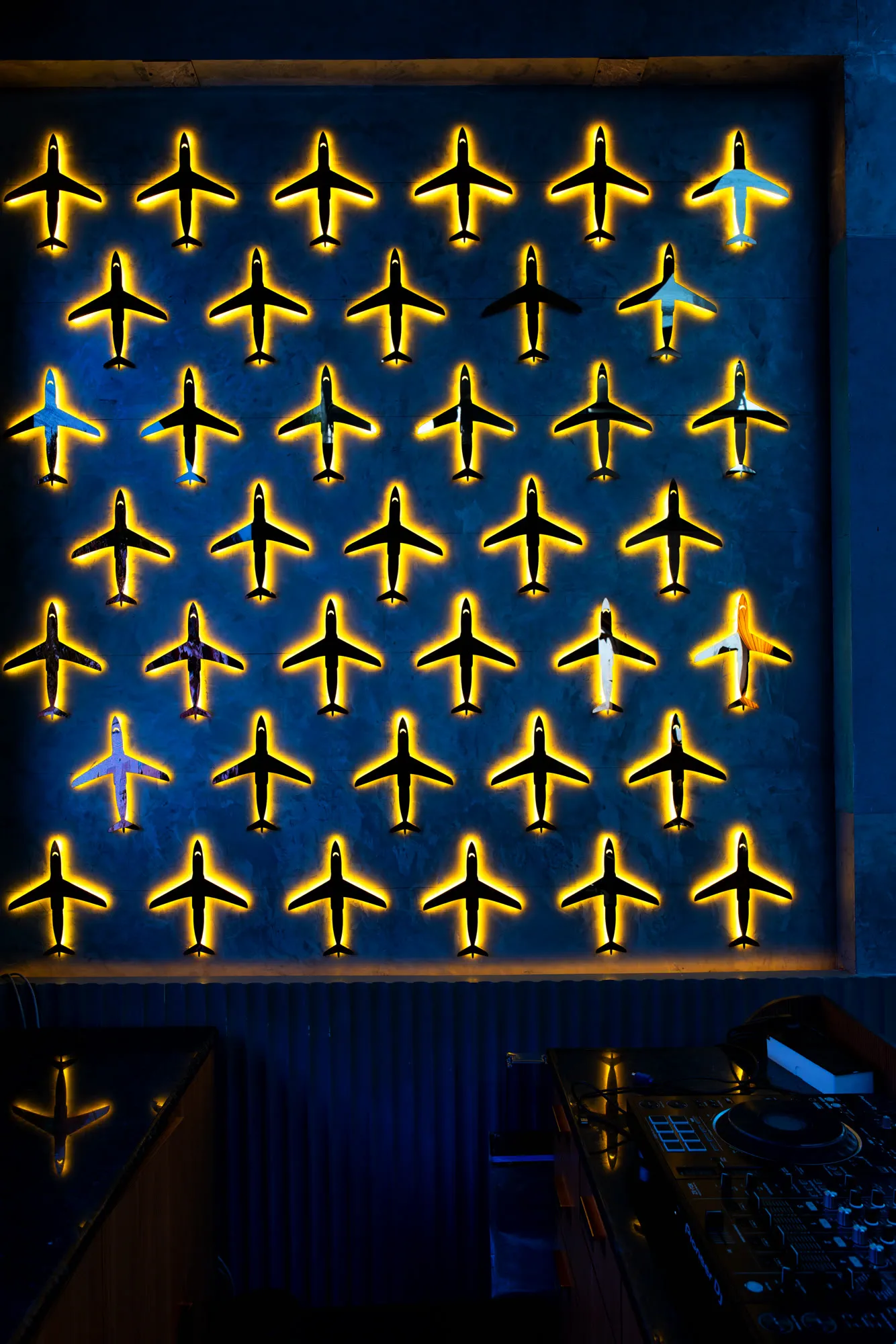 A wall of backlit model aircraft above the DJ deck