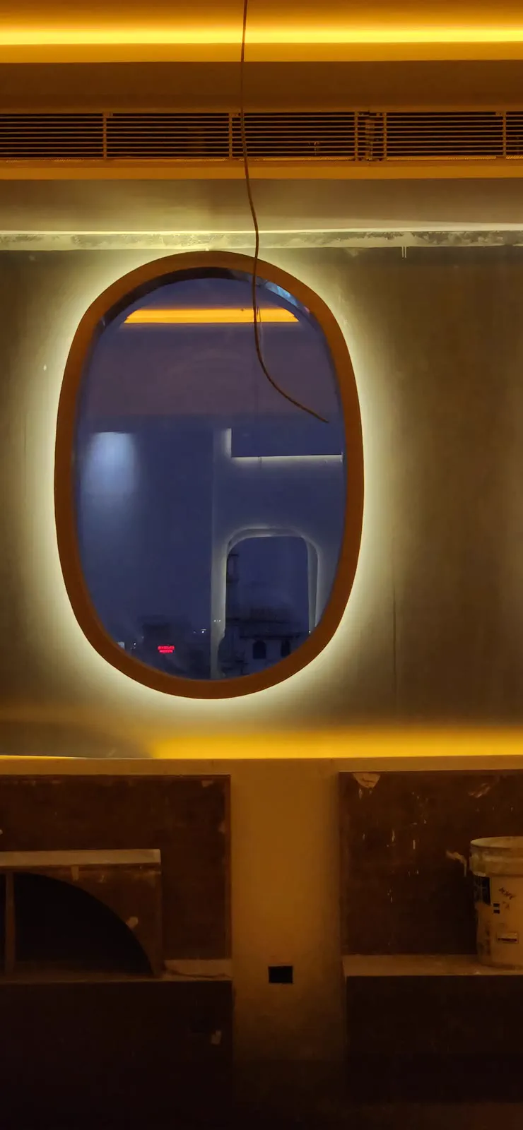 A backlit porthole window, glazed, with the surrounding wall still unfinished