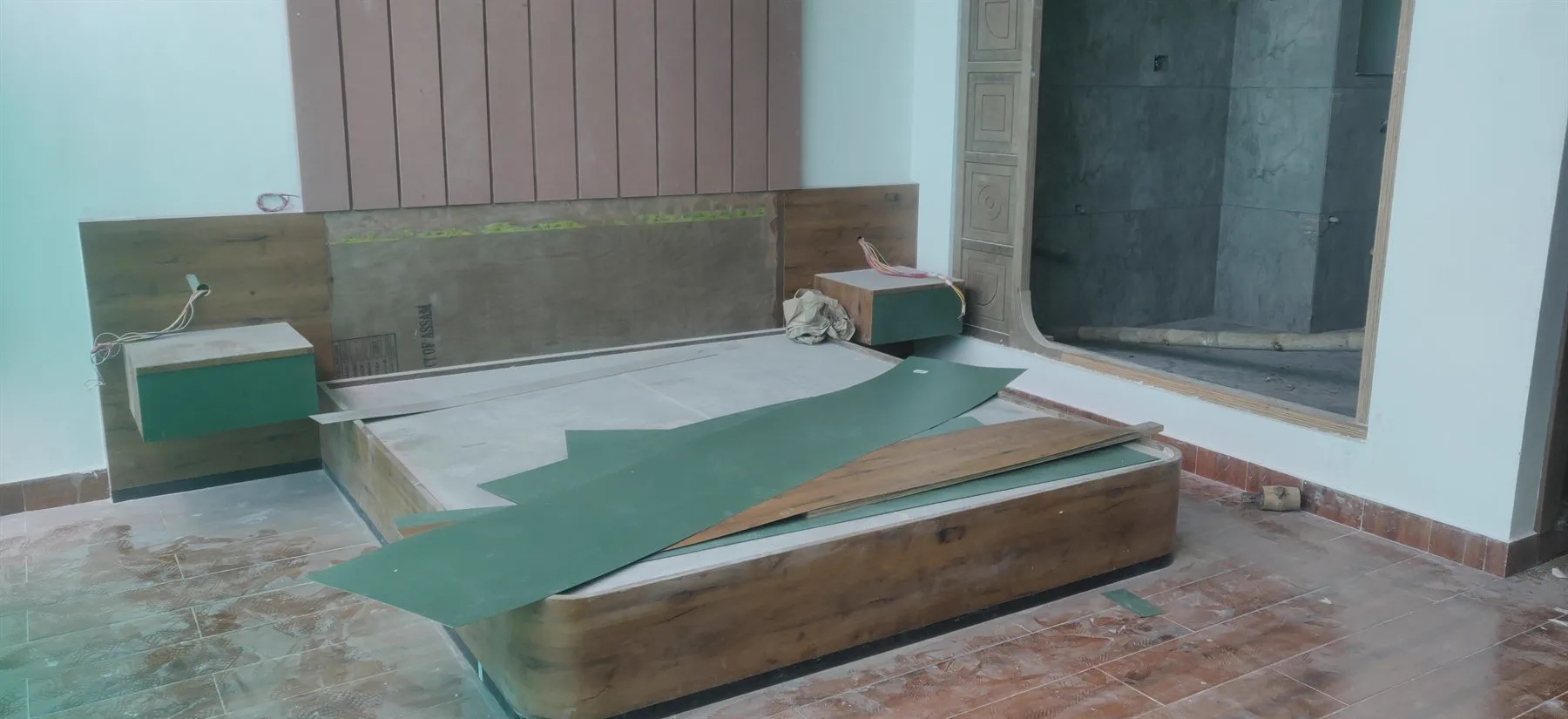 A bed platform and headboard panel being built, with the bathroom opening beyond