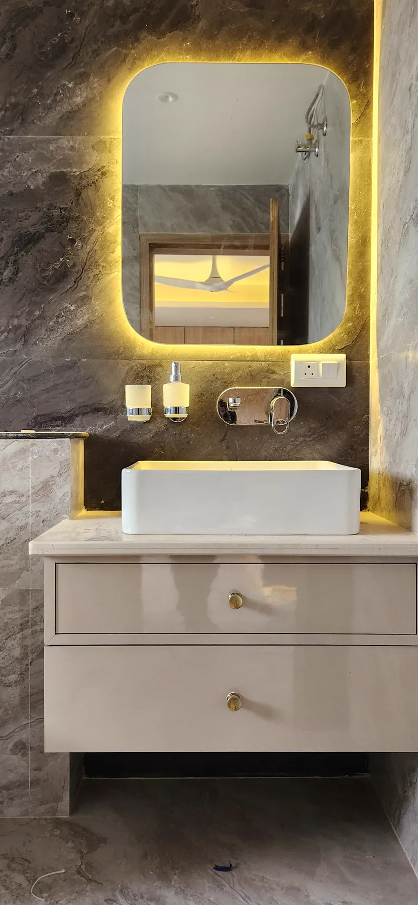 A vessel basin on a floating vanity beneath a backlit mirror