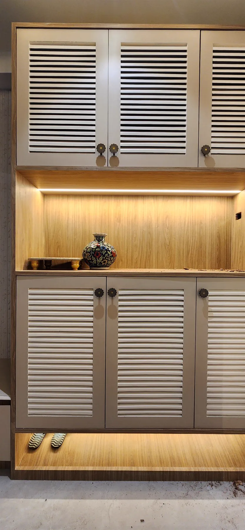 The shoe cabinet installed, with louvred doors and floral knobs