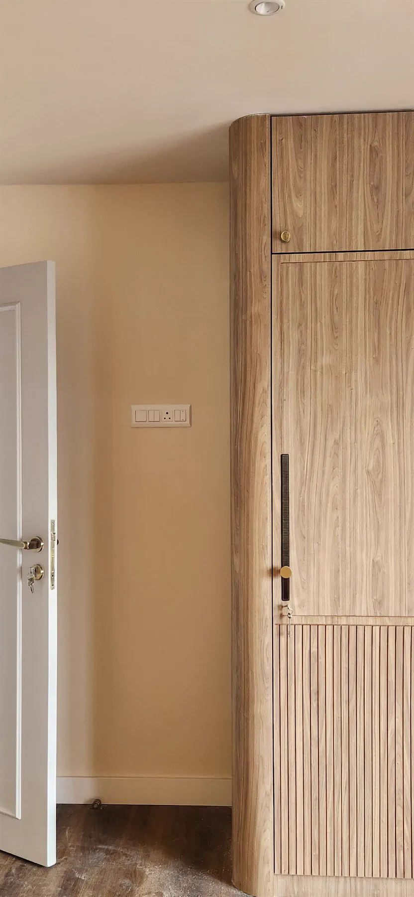 A wardrobe's radiused corner with a brass disc pull set into a fluted panel