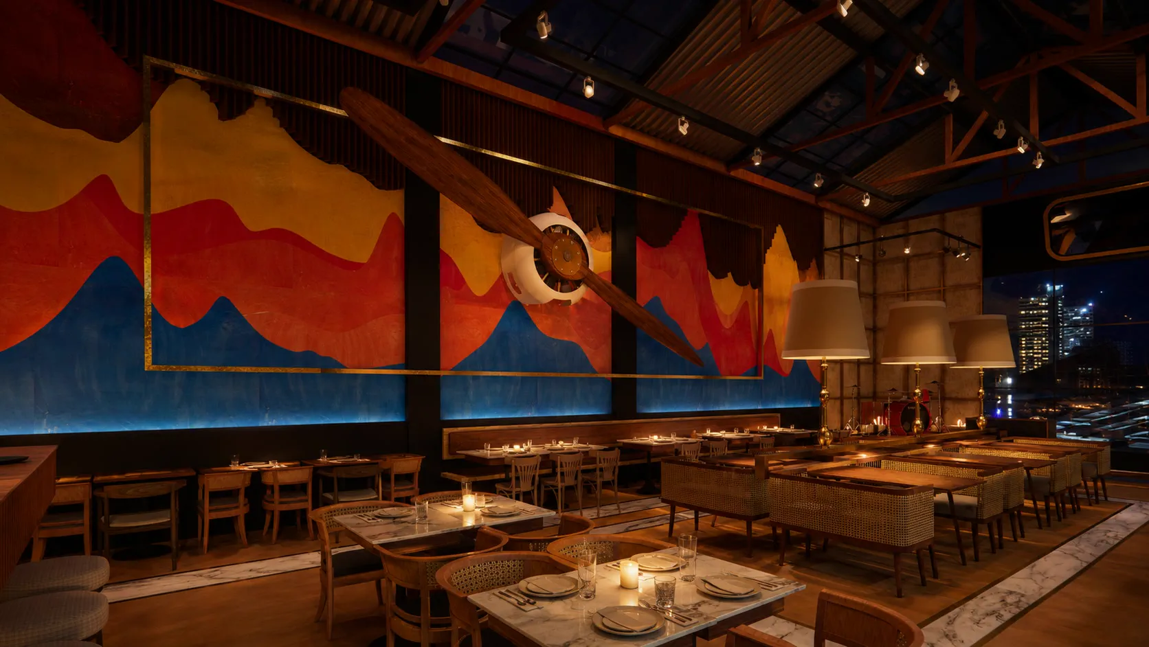 The dining room at night looking towards the stage, cane booths and marble tables beneath the mural