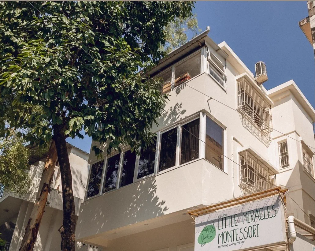 The school from the street, with its signage under the awning and a tree in front