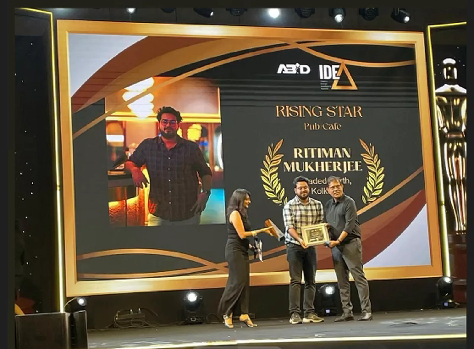 Ritiman Mukherjee accepting the Rising Star award for Pub/Cafe at the ABID IDEA Awards, the screen behind him crediting Headed North, Kolkata