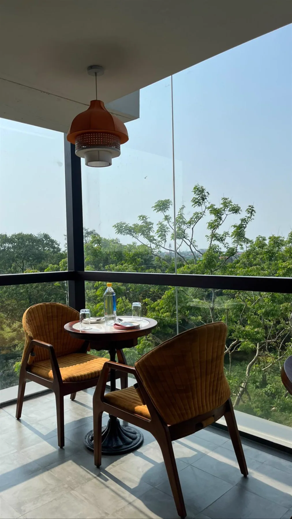 A two-seat table at the corner glazing looking out over the trees