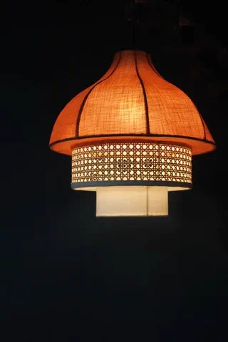 A pendant light in terracotta fabric with a rattan band