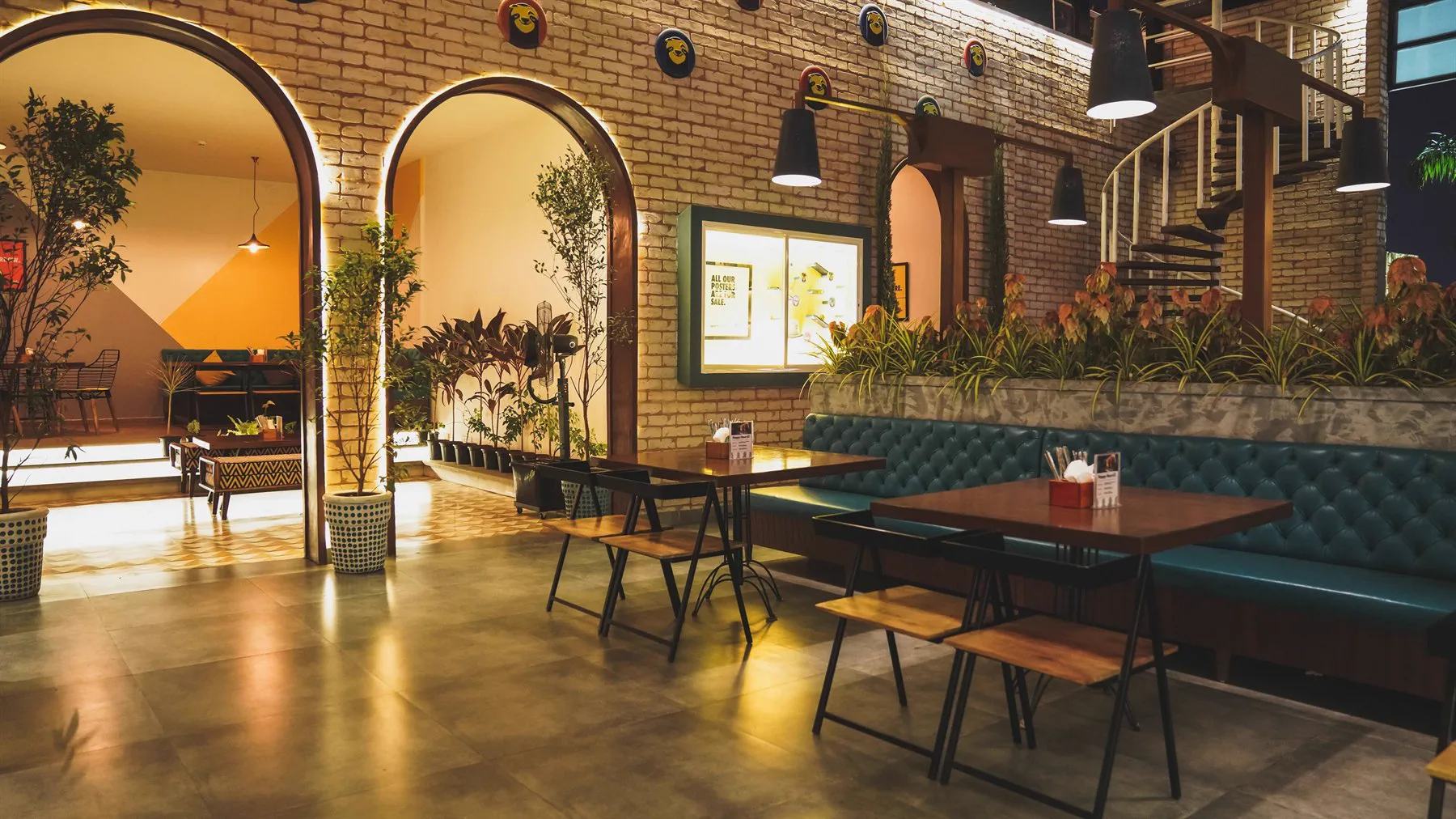 What The Ale at night &mdash; brick arches lit from behind, a teal banquette, and the spiral stair rising to the mezzanine